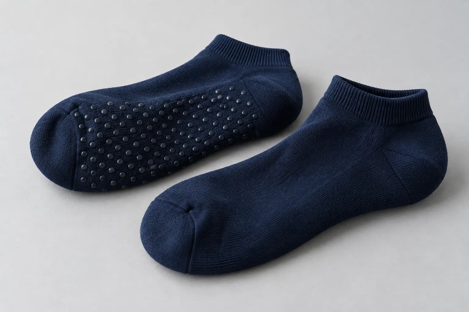Illustrative navy ankle socks showing a dotted grip sole and a side view