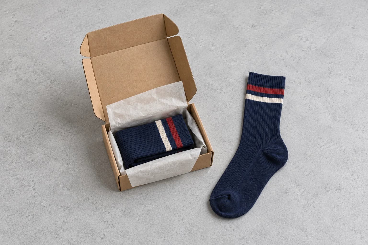 Illustrative navy striped socks in a tissue-lined hinged kraft mailer beside a matching full crew sock